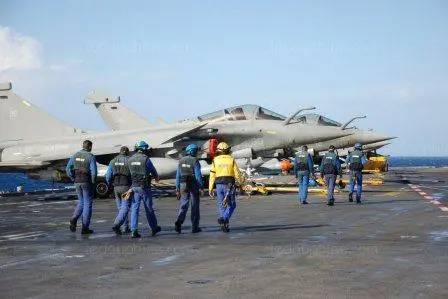 Techniciens sur le pont d'envol d'un porte‑avions préparant les avions Rafale